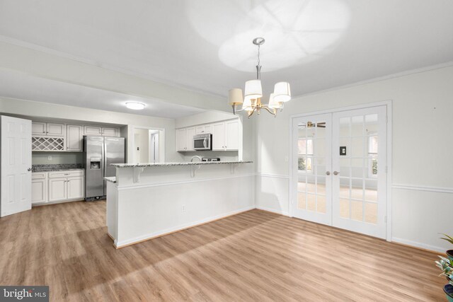 kitchen featuring light hardwood / wood-style floors, french doors, hanging light fixtures, and appliances with stainless steel finishes