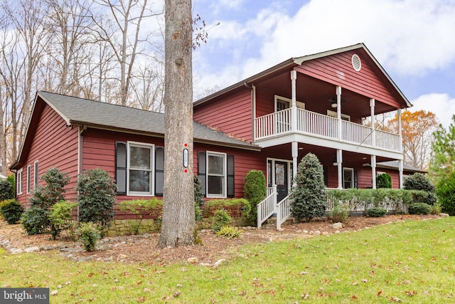 view of front of home featuring ceiling fan, a balcony, and a front yard