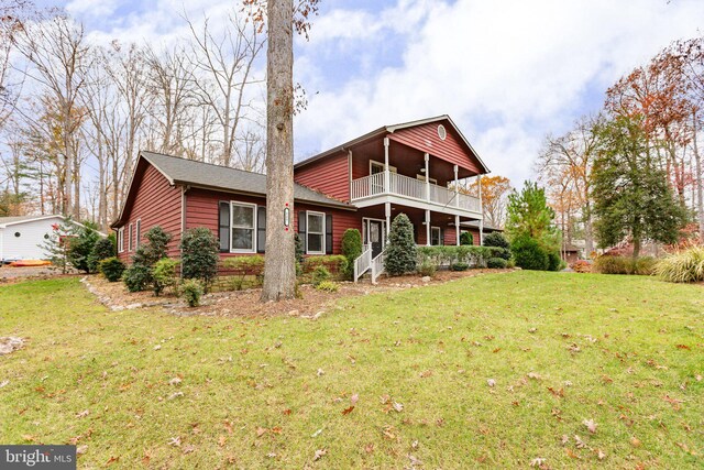 back of house with a lawn and a balcony