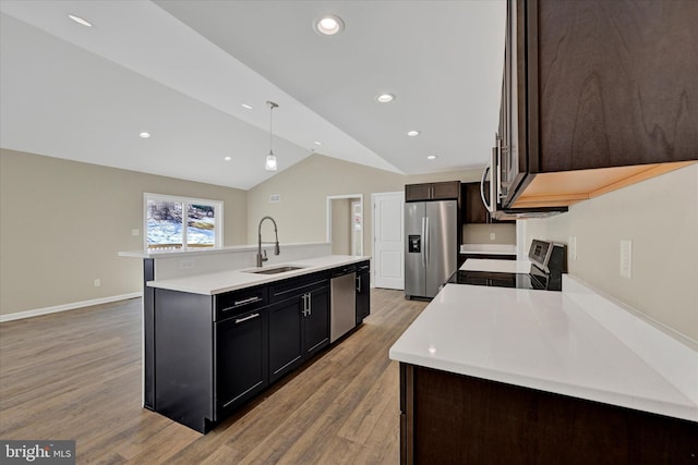 kitchen featuring sink, light hardwood / wood-style flooring, an island with sink, pendant lighting, and stainless steel appliances