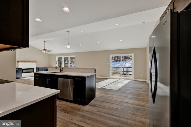 kitchen with lofted ceiling, sink, fridge, a center island with sink, and stainless steel dishwasher