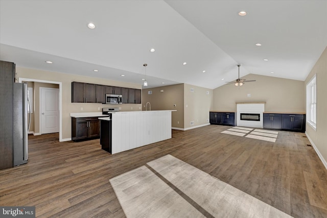 kitchen featuring pendant lighting, dark brown cabinets, stainless steel appliances, an island with sink, and vaulted ceiling