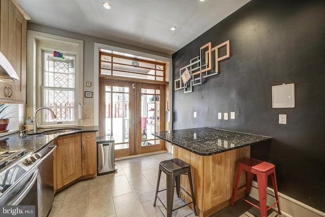 kitchen featuring french doors, a kitchen breakfast bar, plenty of natural light, and dark stone counters