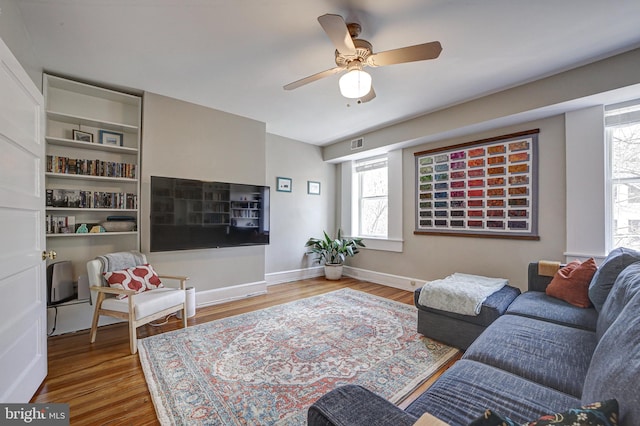 living room with plenty of natural light, wood-type flooring, and ceiling fan