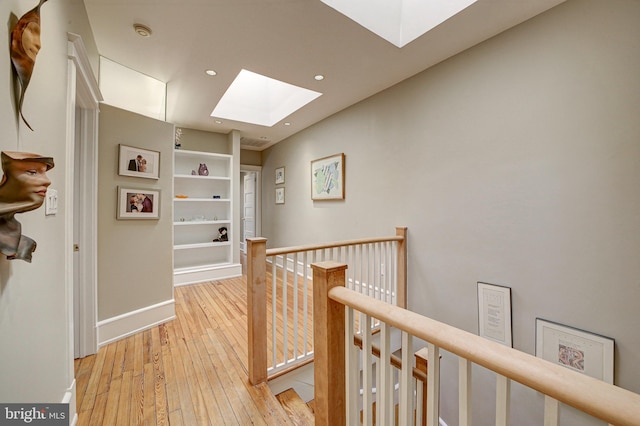 corridor with a skylight and light hardwood / wood-style floors