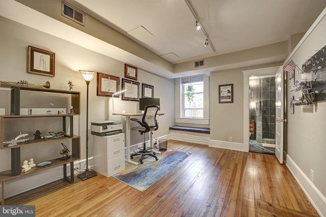 office area with light wood-type flooring and track lighting