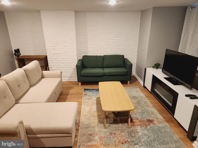 living room with brick wall and light hardwood / wood-style flooring