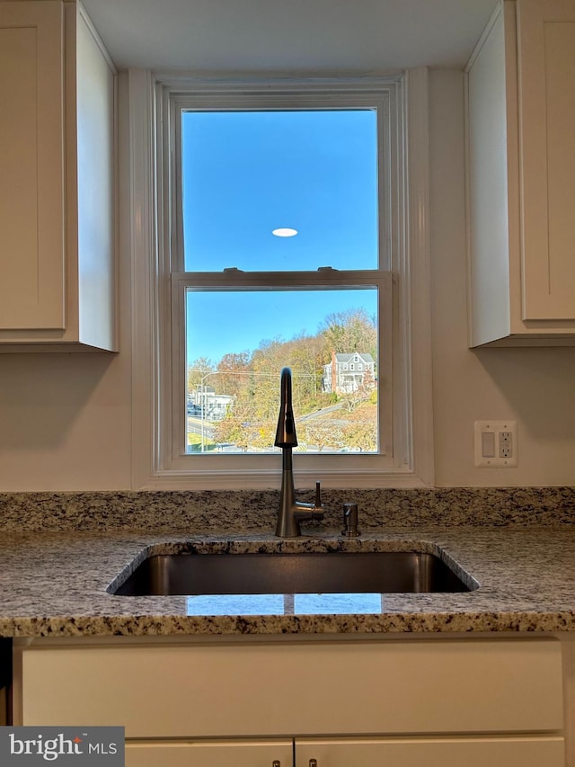 details with white cabinetry, sink, and light stone counters