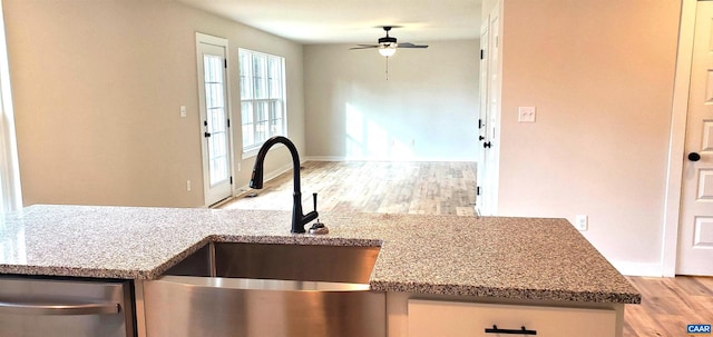 kitchen featuring stainless steel dishwasher, sink, ceiling fan, and light hardwood / wood-style flooring