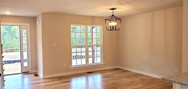 unfurnished dining area with light wood-type flooring and an inviting chandelier