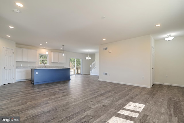 unfurnished living room featuring dark hardwood / wood-style floors, a chandelier, and sink