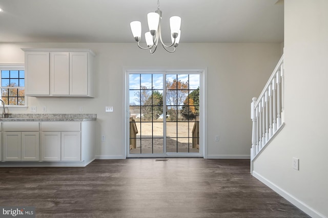 unfurnished dining area featuring a wealth of natural light, dark wood-type flooring, and a chandelier