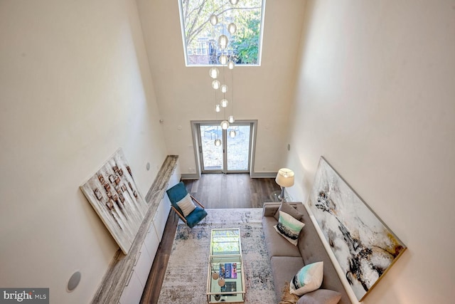 living room with a wealth of natural light, a towering ceiling, and wood-type flooring