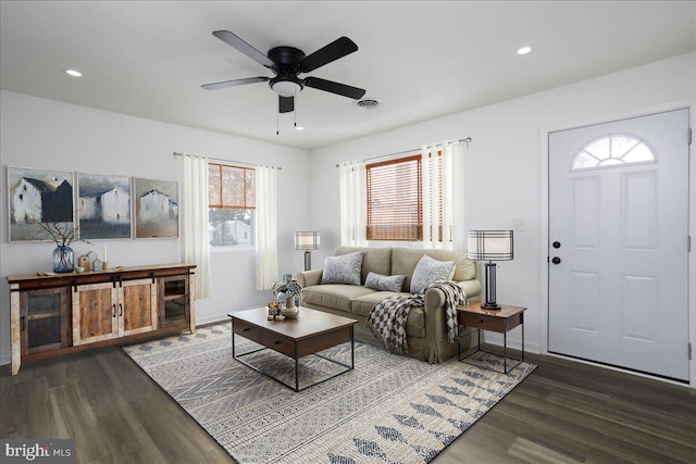 living room featuring ceiling fan and dark hardwood / wood-style floors