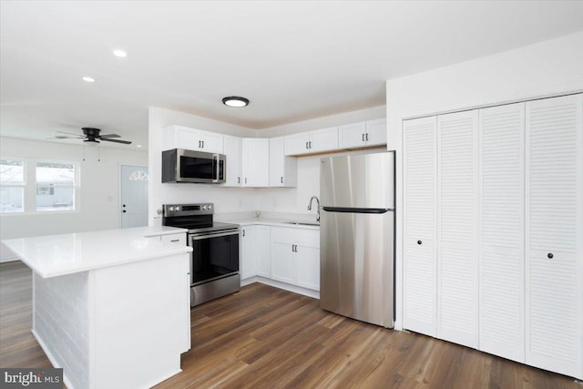 kitchen with kitchen peninsula, sink, ceiling fan, appliances with stainless steel finishes, and white cabinetry