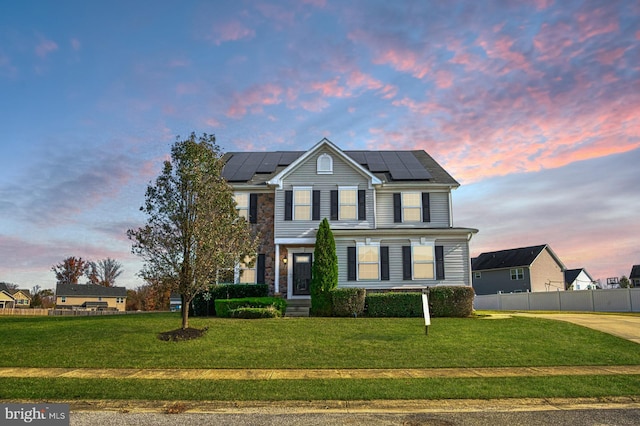 view of front facade featuring solar panels and a lawn