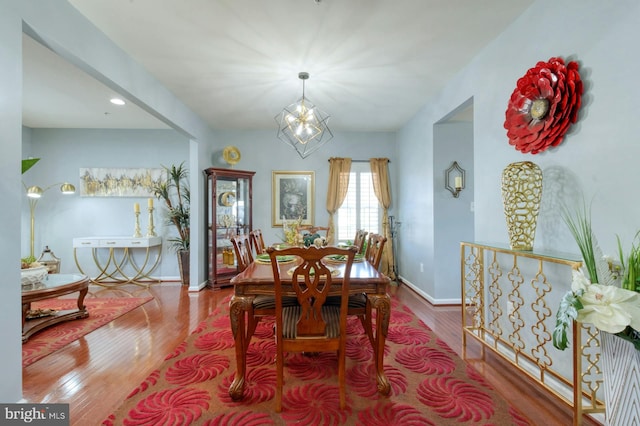 dining space with hardwood / wood-style floors and an inviting chandelier