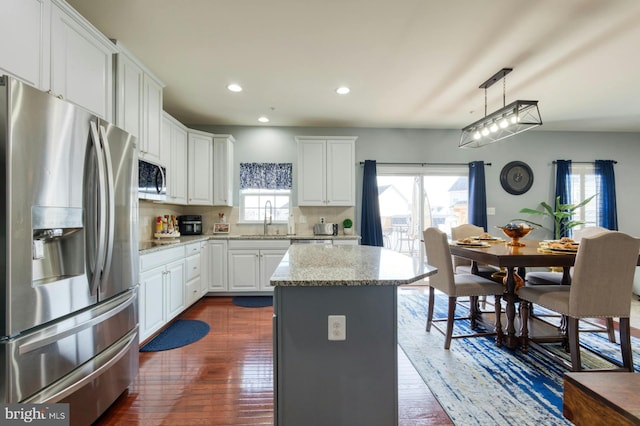 kitchen featuring hanging light fixtures, appliances with stainless steel finishes, a center island, and a wealth of natural light