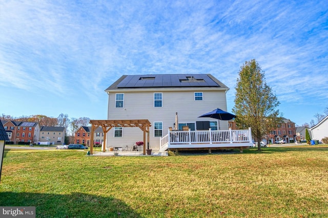 back of house with solar panels, a pergola, a deck, and a yard