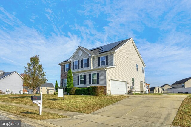 view of front of property featuring solar panels, a garage, and a front lawn