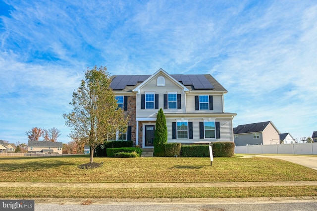 view of front of home with solar panels and a front lawn