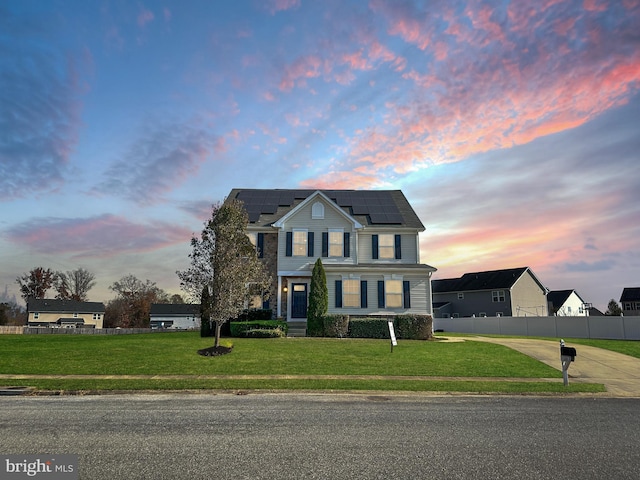 view of front of property featuring a lawn and solar panels