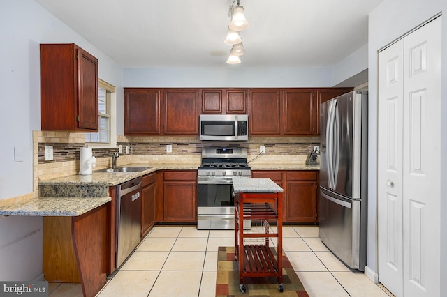 kitchen with sink, decorative backsplash, light tile patterned floors, light stone counters, and stainless steel appliances