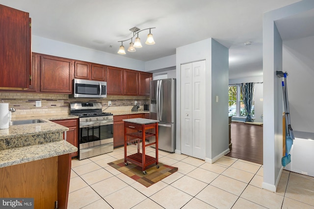 kitchen featuring sink, stainless steel appliances, tasteful backsplash, light stone counters, and light tile patterned floors