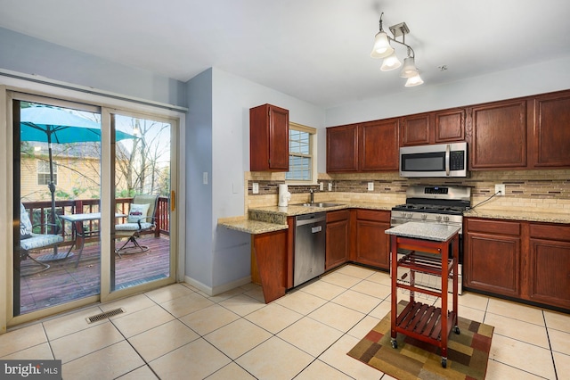 kitchen featuring backsplash, light stone countertops, sink, and stainless steel appliances