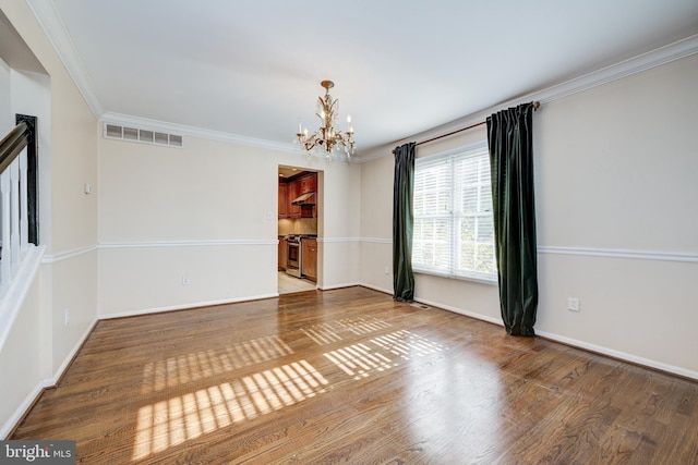 empty room with a chandelier, wood-type flooring, and crown molding