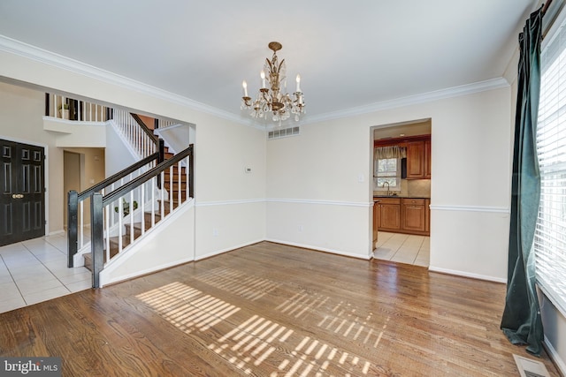 unfurnished room with a chandelier, ornamental molding, and light hardwood / wood-style flooring