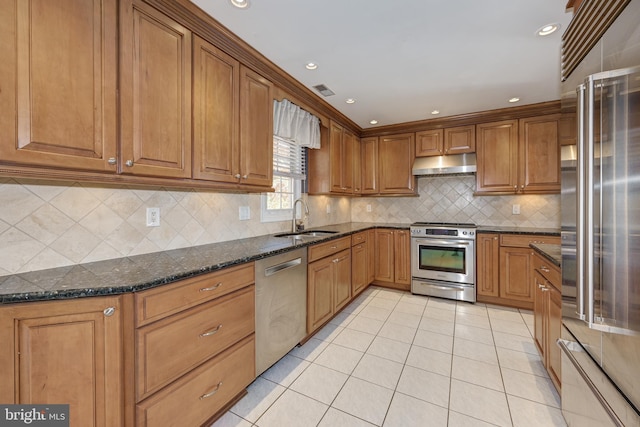 kitchen with dark stone counters, tasteful backsplash, sink, and stainless steel appliances