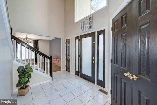 entryway featuring a notable chandelier, light tile patterned flooring, a high ceiling, and a wealth of natural light