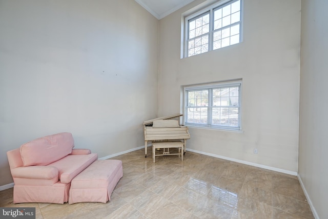 living area featuring a high ceiling, crown molding, and a healthy amount of sunlight