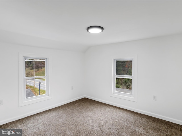 carpeted empty room with vaulted ceiling