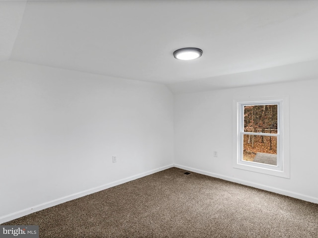 spare room with carpet flooring and lofted ceiling