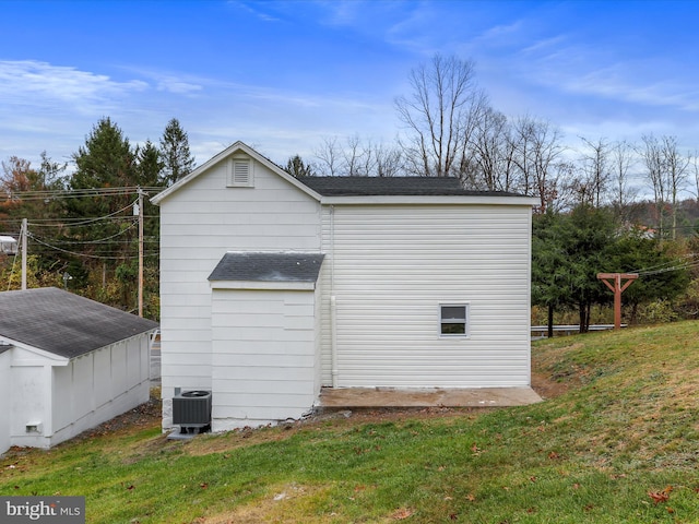 view of property exterior featuring a lawn, cooling unit, and a storage shed