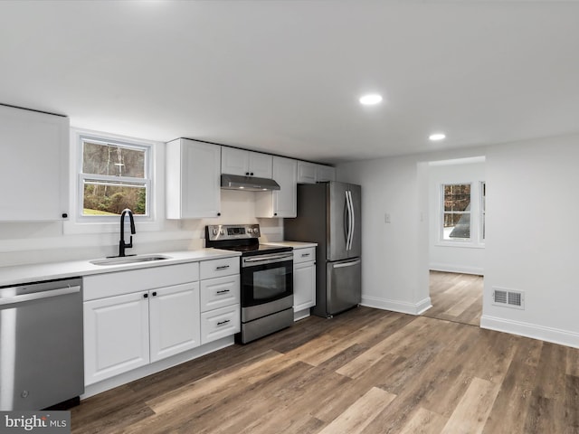 kitchen featuring white cabinetry, sink, stainless steel appliances, and hardwood / wood-style flooring