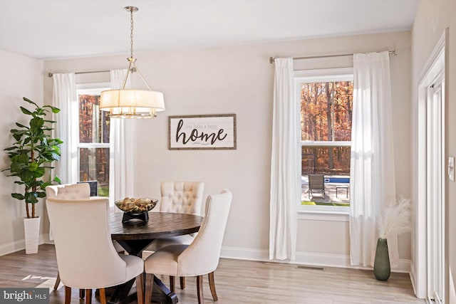 dining space featuring a chandelier, baseboards, and light wood-style flooring