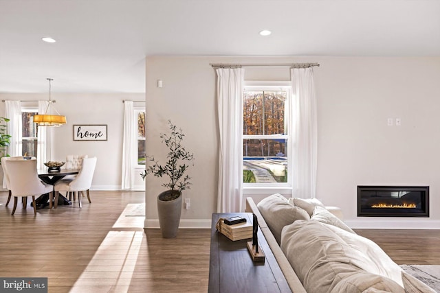 living area with wood finished floors, recessed lighting, a glass covered fireplace, and baseboards