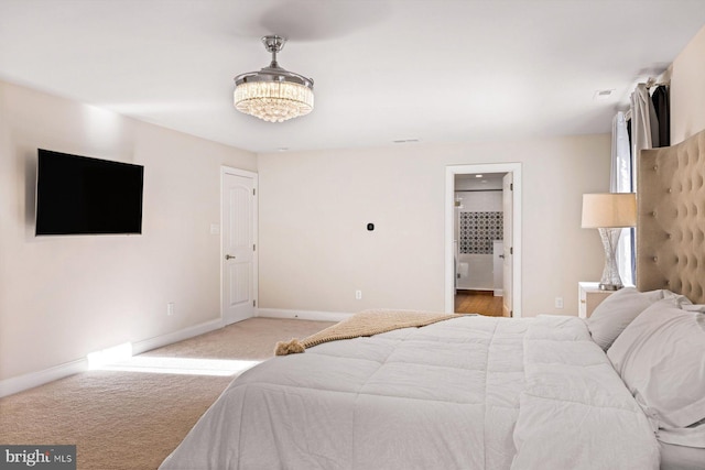 carpeted bedroom featuring baseboards and connected bathroom