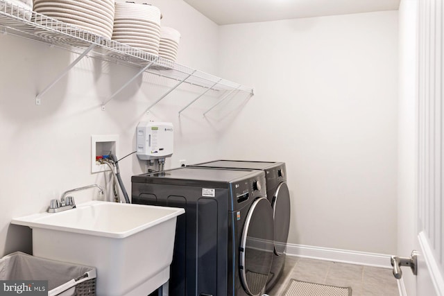 washroom with washing machine and clothes dryer, baseboards, and tile patterned flooring