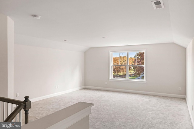carpeted spare room featuring vaulted ceiling and baseboards