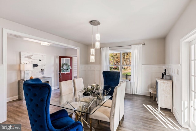 dining area featuring wood finished floors, wainscoting, and a decorative wall