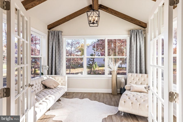 sunroom / solarium featuring healthy amount of natural light, baseboards, wood finished floors, and a chandelier