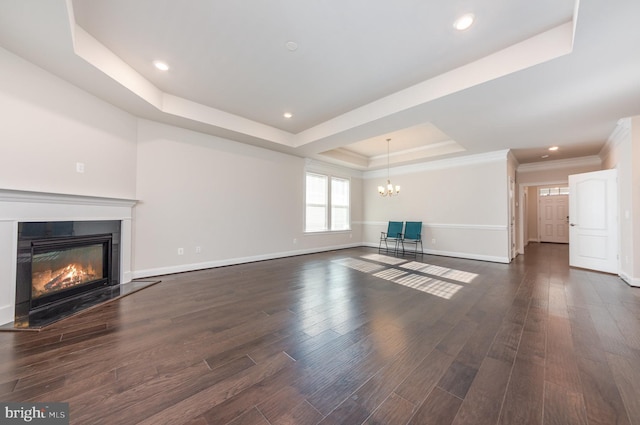 unfurnished living room featuring an inviting chandelier, ornamental molding, dark wood-type flooring, and a tray ceiling