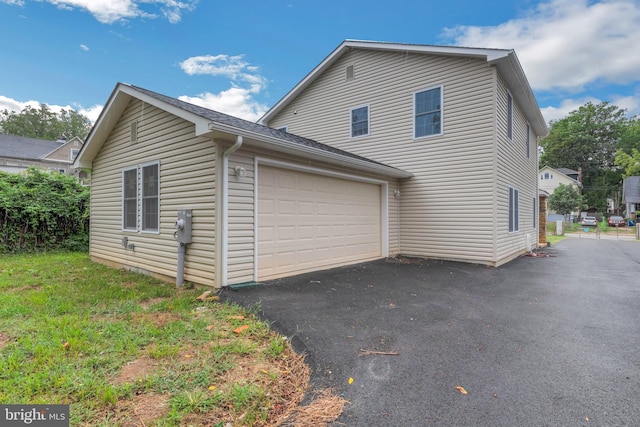 view of side of property featuring driveway and an attached garage