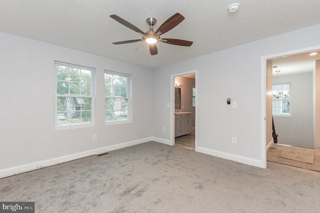 unfurnished bedroom with carpet, multiple windows, ensuite bathroom, and ceiling fan