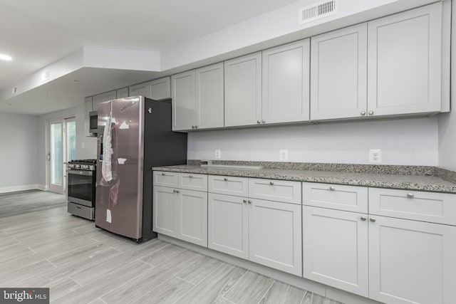 kitchen with light stone countertops, stainless steel appliances, and white cabinetry