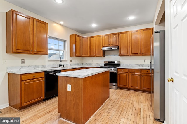 kitchen featuring stainless steel appliances, light hardwood / wood-style floors, sink, a kitchen island, and a barn door